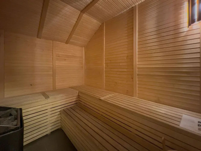 A wooden sauna with ceiling and tile floor.