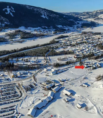 Luchtfoto van een besneeuwd dorp met wegen, huizen en een wintersportgebied, met bergen en een bevroren vallei op de achtergrond..